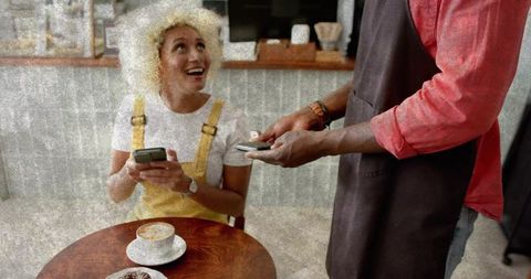 Woman in Café Paying Contactless with Joyful Expression