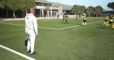 Coach observing soccer practice on bright sunny field