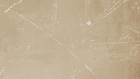 Worn beige paper texture featuring scratches, flecks and subtle patina for backgrounds