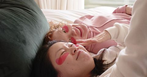 Friends relaxing with pink heart under-eye patches during cozy at-home skincare