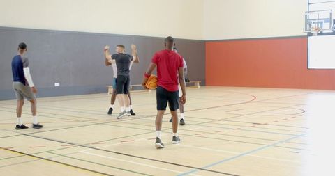 Man holding basketball leading casual indoor pickup game on bright hardwood court