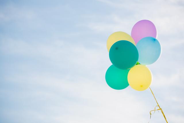 Bunch of pastel color balloons floating in the air against blue sky
