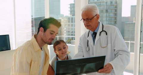 Senior Doctor Discussing X-ray with Family in Modern Clinic - Download Free Stock Images Pikwizard.com