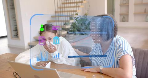 Mature woman guiding teen using laptop with augmented reality data overlays for learning