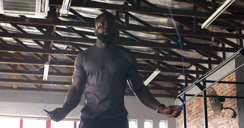 Athletic African American Man Jumping Rope in Industrial Gym
