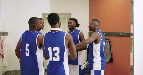 Basketball team huddling in locker room planning game strategy and building team energy