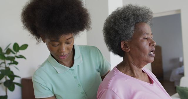 Happy african american female physiotherapist helping senior female patient exercise at home. senior healthcare and medical physiotherapy treatment.