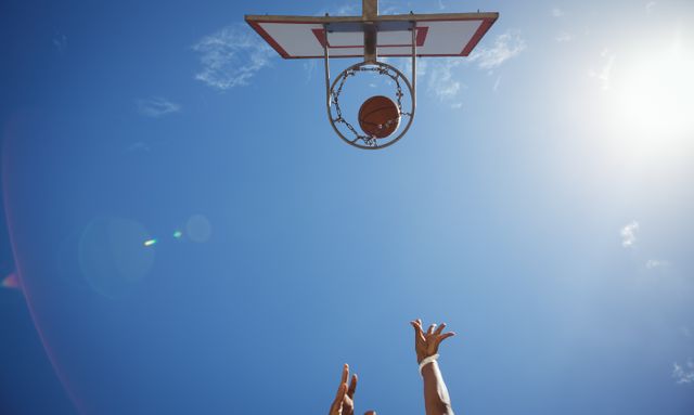 Perfect for sports-related content, motivational posters, or advertisements promoting outdoor activities and fitness. Captures the dynamic action of a basketball game with a clear blue sky background, emphasizing athleticism and outdoor recreation.