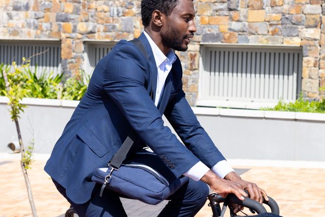 African american businessman in suit riding a bike. Business, work, corporation, recreation and healthy lifestyle concept.