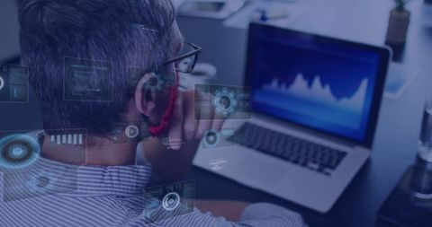 Analyst Engaging with Data Graphics on Laptop at Office Desk