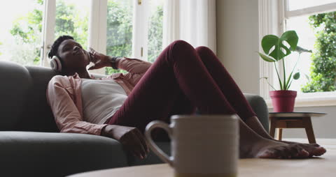 Relaxed Woman Enjoying Music on Couch at Home