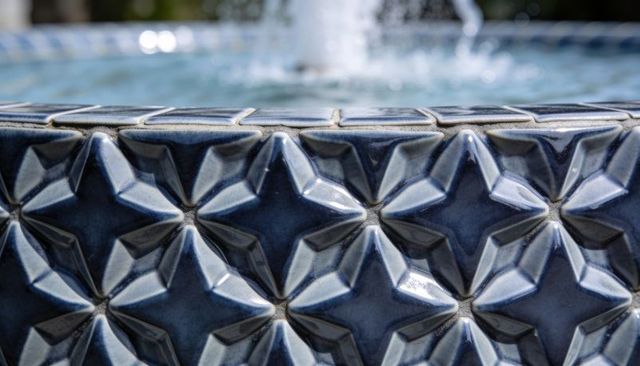 Blue glazed ceramic band with raised star tiles around fountain rim tessellated pattern