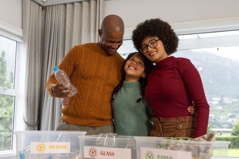Multicultural family sorting recyclables together at home for sustainable living and recycling