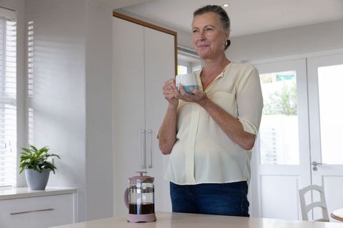 Senior Woman Enjoying Coffee in Bright Modern Kitchen with French Press