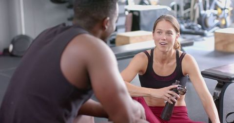 Diverse Gym Pair in Conversation During Matched Workout Routine