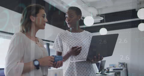 Businesswomen Collaborating with Financial Data Overlay in Modern Office