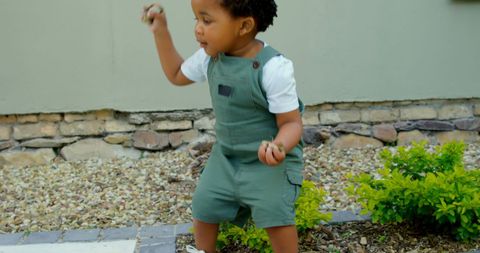 Toddler joyfully playing outside near short bushes