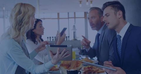 Team presenting during breakfast meeting in modern cafe with tablets and coffee