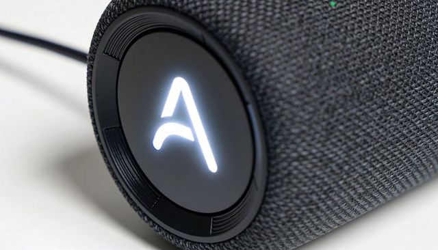 Modern smart speaker illuminated a logo woven fabric grille closeup