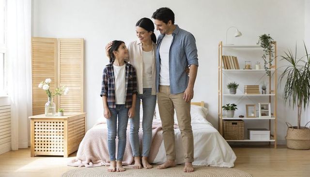 Modern family sharing tender morning moment in bright minimalist scandinavian bedroom