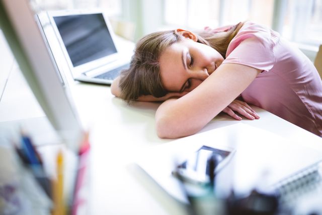 Tired graphic designer sleeping at desk in creative office