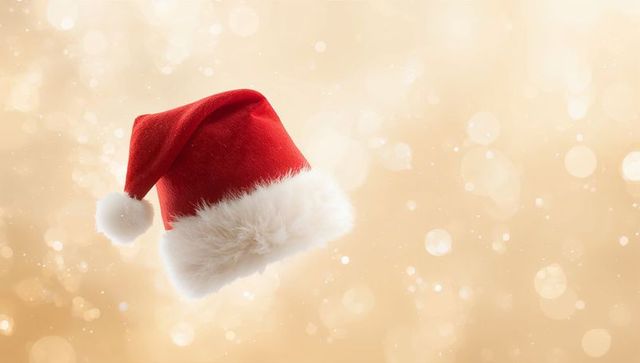Floating Santa Hat with Plush Fur Trim and Pom-Pom on Warm Golden Bokeh Background