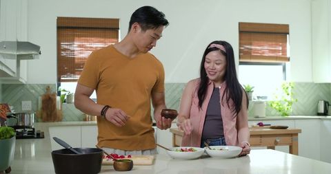 Couple preparing fresh colorful salads on modern kitchen island, casual home cooking