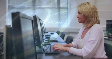 Typing Woman in Computer Lab Using Desktop Monitors, Focused on Learning and Productivity