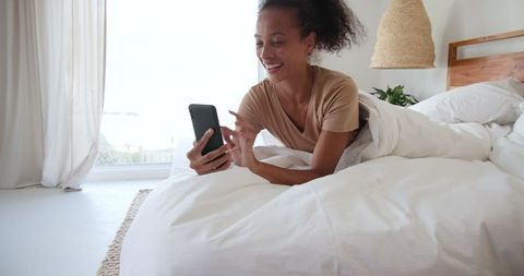 Relaxed Woman Using Smartphone in Cozy Bedroom Setting