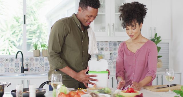 Happy african american couple cooking and dumping waste in kitchen. Spending quality time at home together concept.
