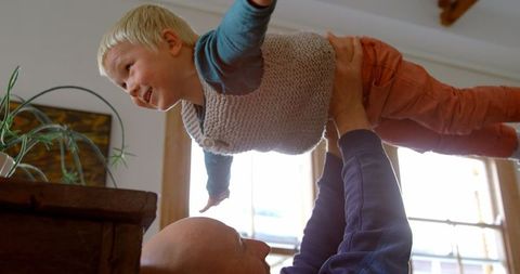 Father bonding with joyful child in living room filled with natural light