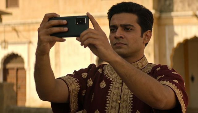 Man taking selfie in ornate arched courtyard wearing maroon embroidered kurta