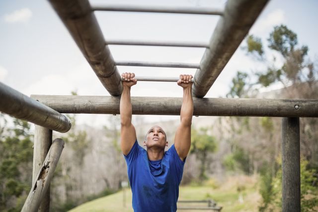 Fit man climbing monkey bars during obstacle course in boot camp