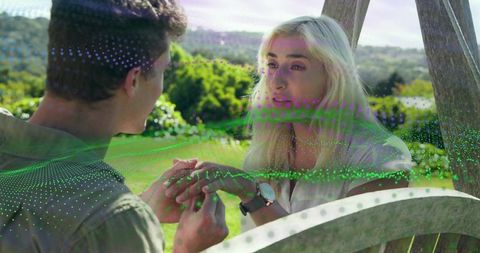 Young couple holding hands on wooden swing with holographic digital mesh overlay in meadow