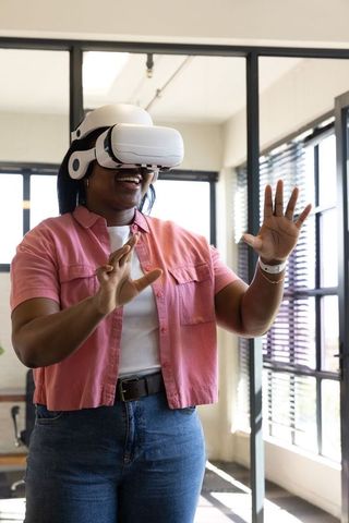African american woman wearing vr headset interacting with virtual interface in office