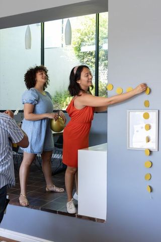 Joyful friends hanging garland for celebration at modern home