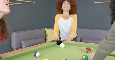 Young Women Laughing and Playing Pool in Modern Game Room Enjoying Billiards Night