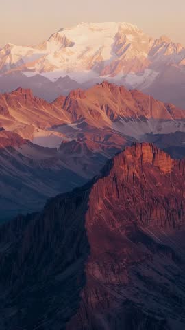Vertical Dawn Alpenglow Revealing Layered Alpine Peaks Ascending Past Snow-Capped Summit