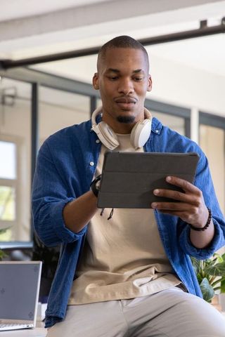 African american professional using tablet in bright coworking space with headphones