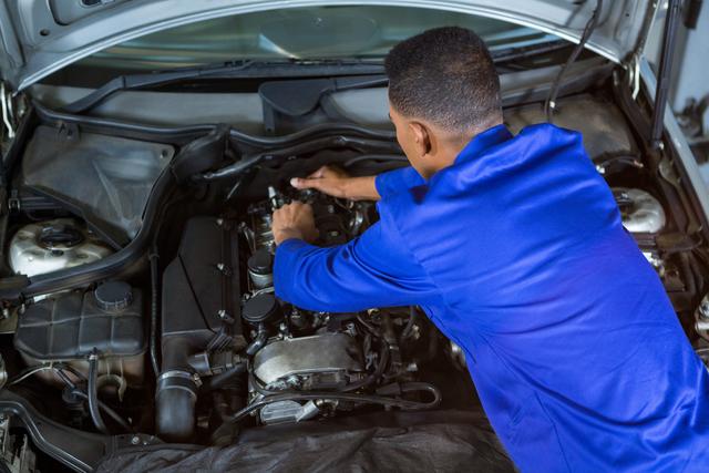 Attentive mechanic servicing automobile car engine in repair garage