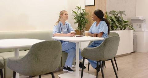Nurses sharing coffee break in modern staff lounge promoting teamwork and wellbeing