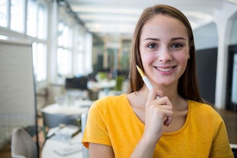 Confident woman in open-plan office holding pen
