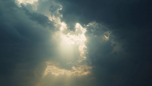 Sunlight piercing storm clouds with dramatic crepuscular rays and backlit cloud edges