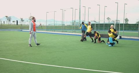 Field hockey team practice with coach on artificial turf field