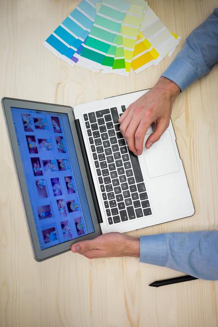 Hands of male graphic designer using laptop in office