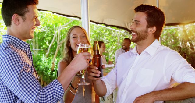 This vibrant scene captures three friends toasting drinks at an outdoor bar. Everyone is smiling and clearly enjoying themselves, highlighting the fun and celebratory nature of the moment. Ideal for use in advertisements promoting social events, alcohol brands, friendship, and general leisure activities during summer. Perfect for illustrating the joy of companionship and outdoor gatherings.