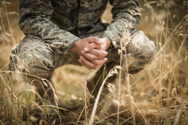 Military soldier crouching in grass in boot camp