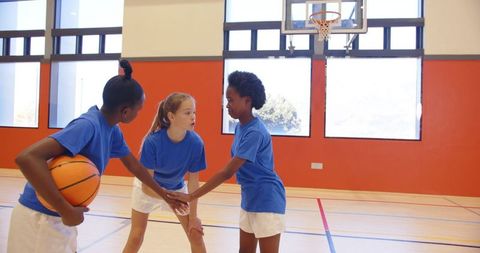 Girls basketball team discussing strategy in school gym