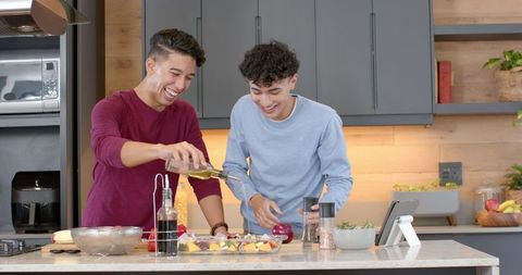 Smiling Friends Cooking Together with Fresh Vegetables in Modern Kitchen