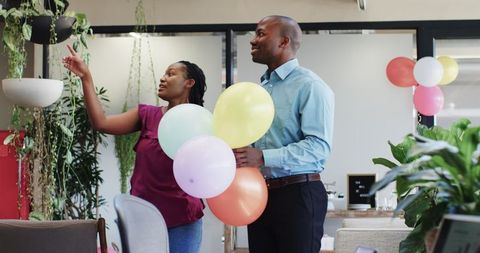 Happy colleagues celebrating office party with colorful balloons